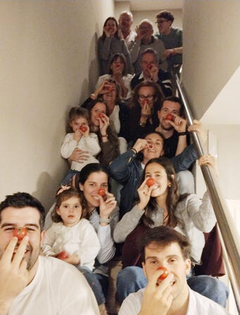 Grup de família fent-se una fotografia a les escales amb tomàquets fent de nas vermell improvisat